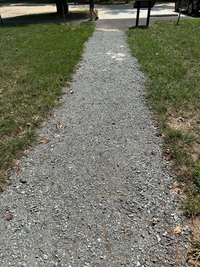 A short flat gravel trail alongside Potomac Crossing Park that becomes rough at the woods